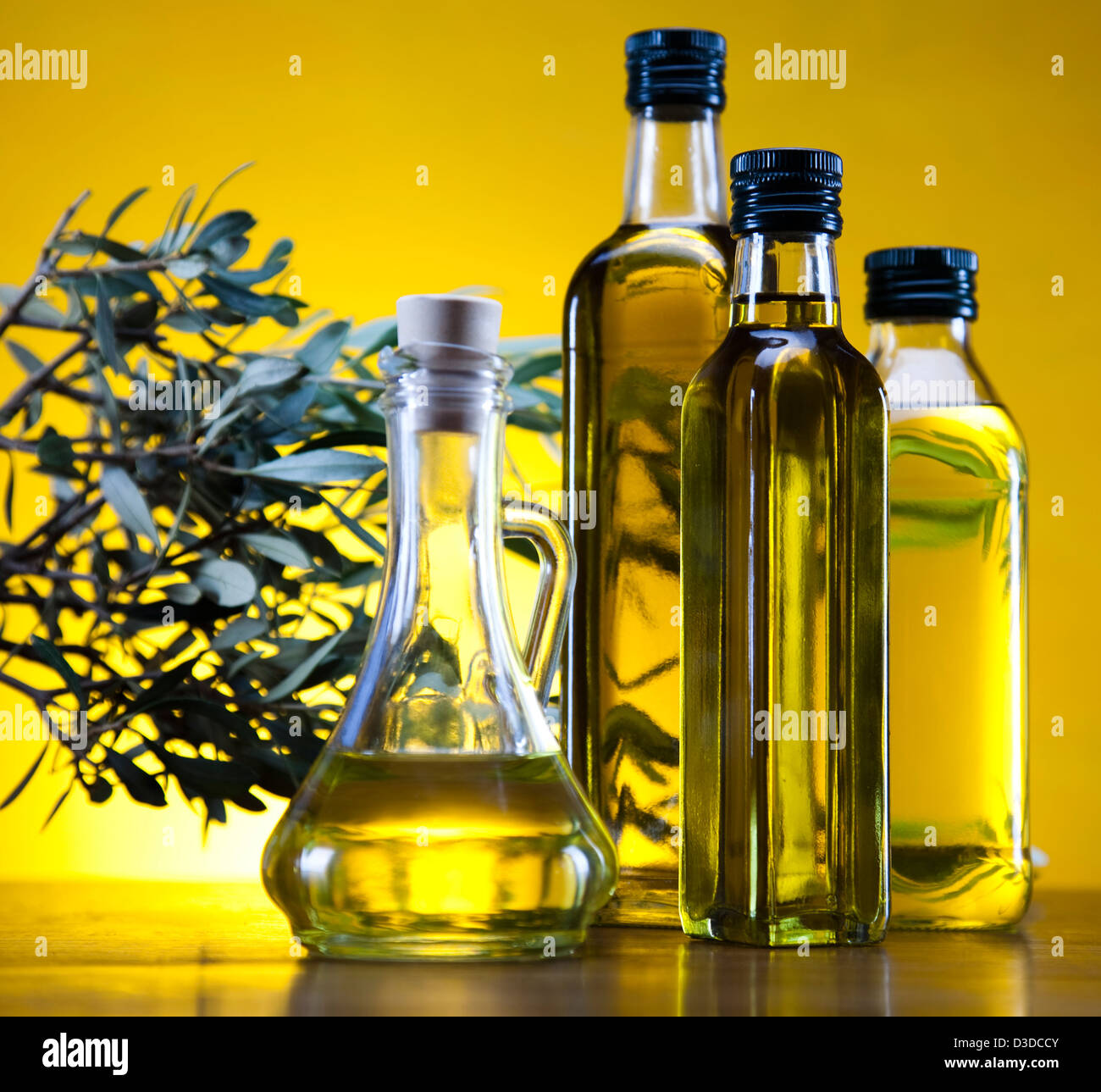 Olivenölflasche mit einigen Blättern Stockfoto