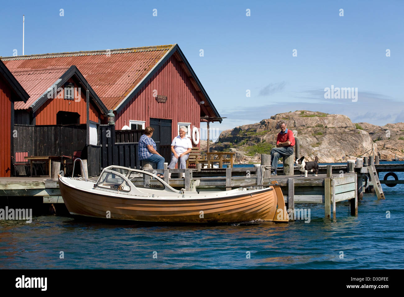 Fjällbacka, Schweden, Einheimische sitzen auf den Holzstegen ihre Bootshaeuser Stockfoto