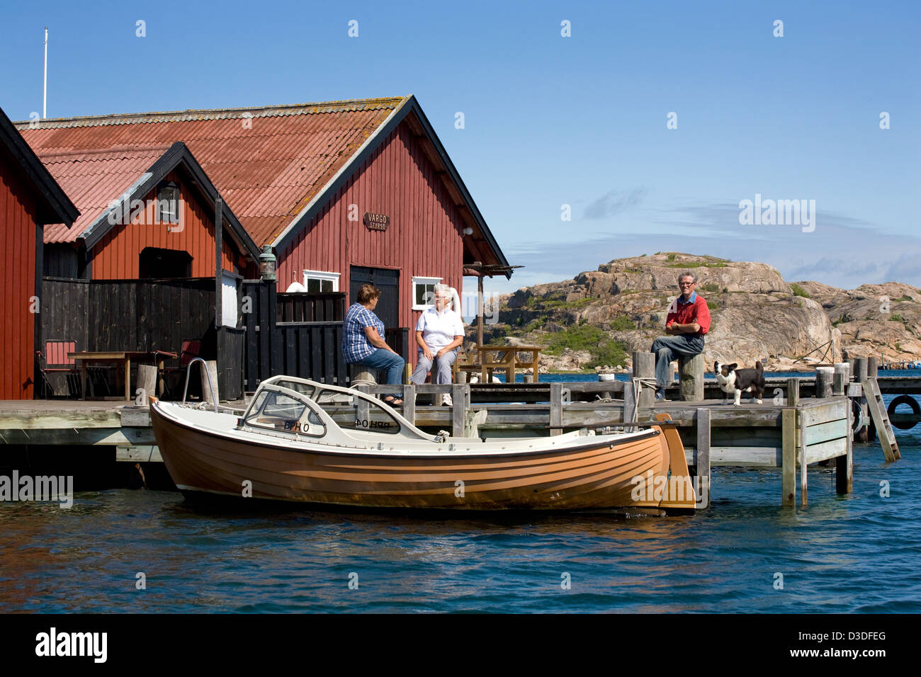 Fjällbacka, Schweden, Einheimische sitzen auf den Holzstegen ihre Bootshaeuser Stockfoto