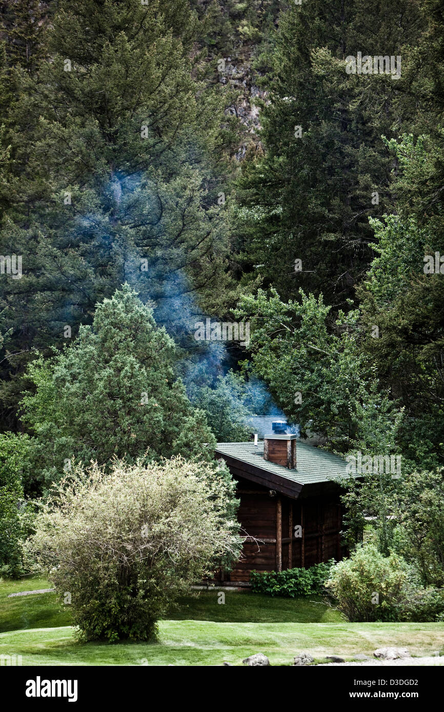 Rauch aus Schornstein der Blockhütte am Berg Sky Ranch, Montana, USA Stockfoto