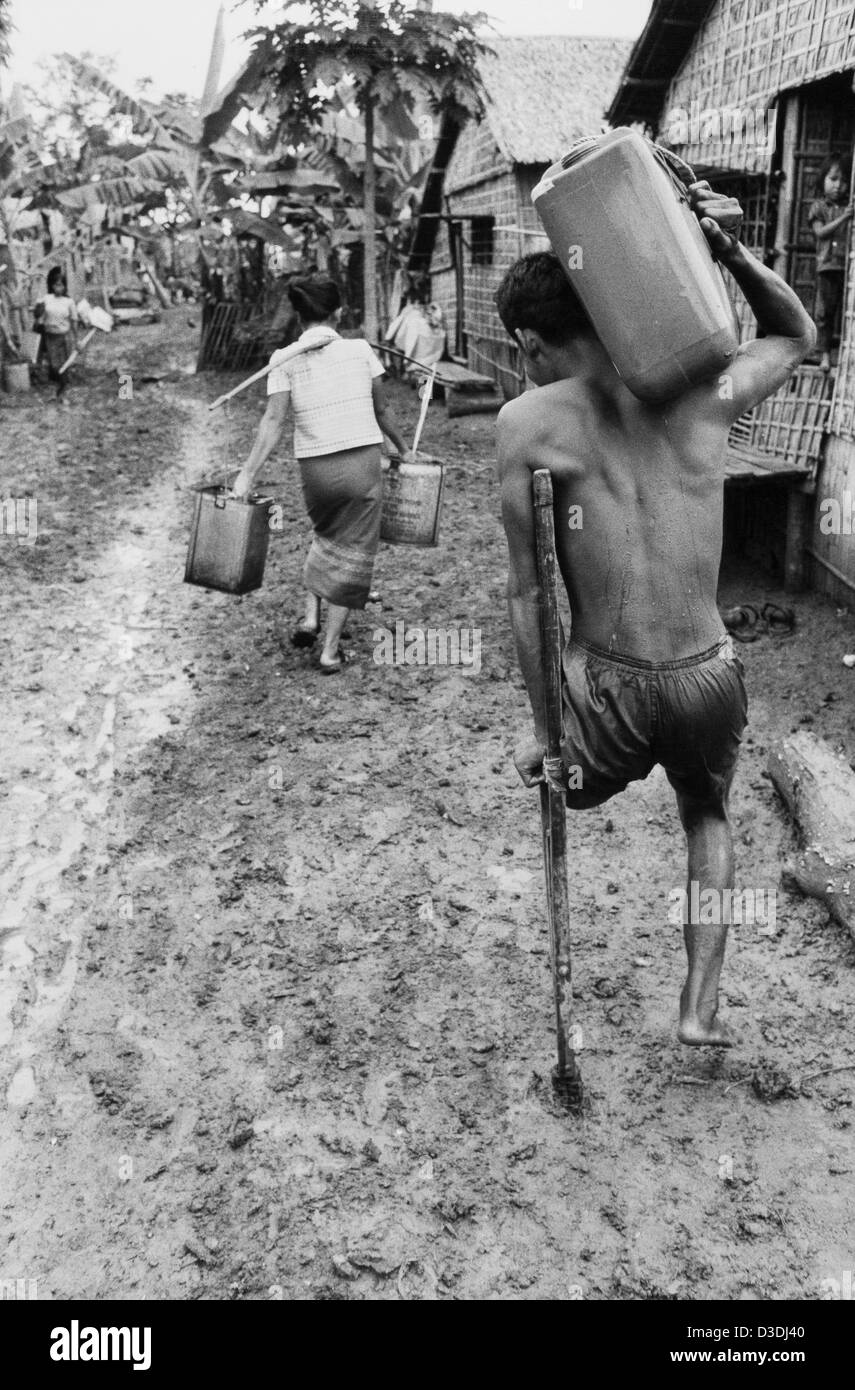Der thailändisch - kambodschanischen Grenze, Thailand: Seite 8, das Khmer Rouge "Schaufenster" Lager 2 km von der Grenze entfernt, beherbergt 33.000 Menschen. . Hier trägt ein KR-Soldat, der verloren hat, ein Bein auf eine Mine treten Wasser zurück zu seinem Haus. Stockfoto