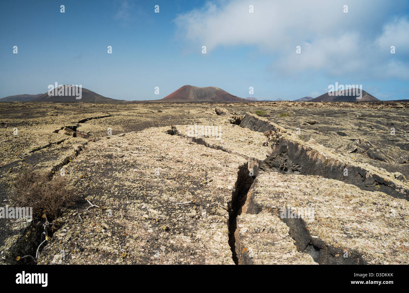 Zerklüftet, mit Flechten bedeckten basaltische Lava in der Nähe von Masdache, Lanzarote mit Montanas Negra, Colorada und Ortiz im Hintergrund Stockfoto