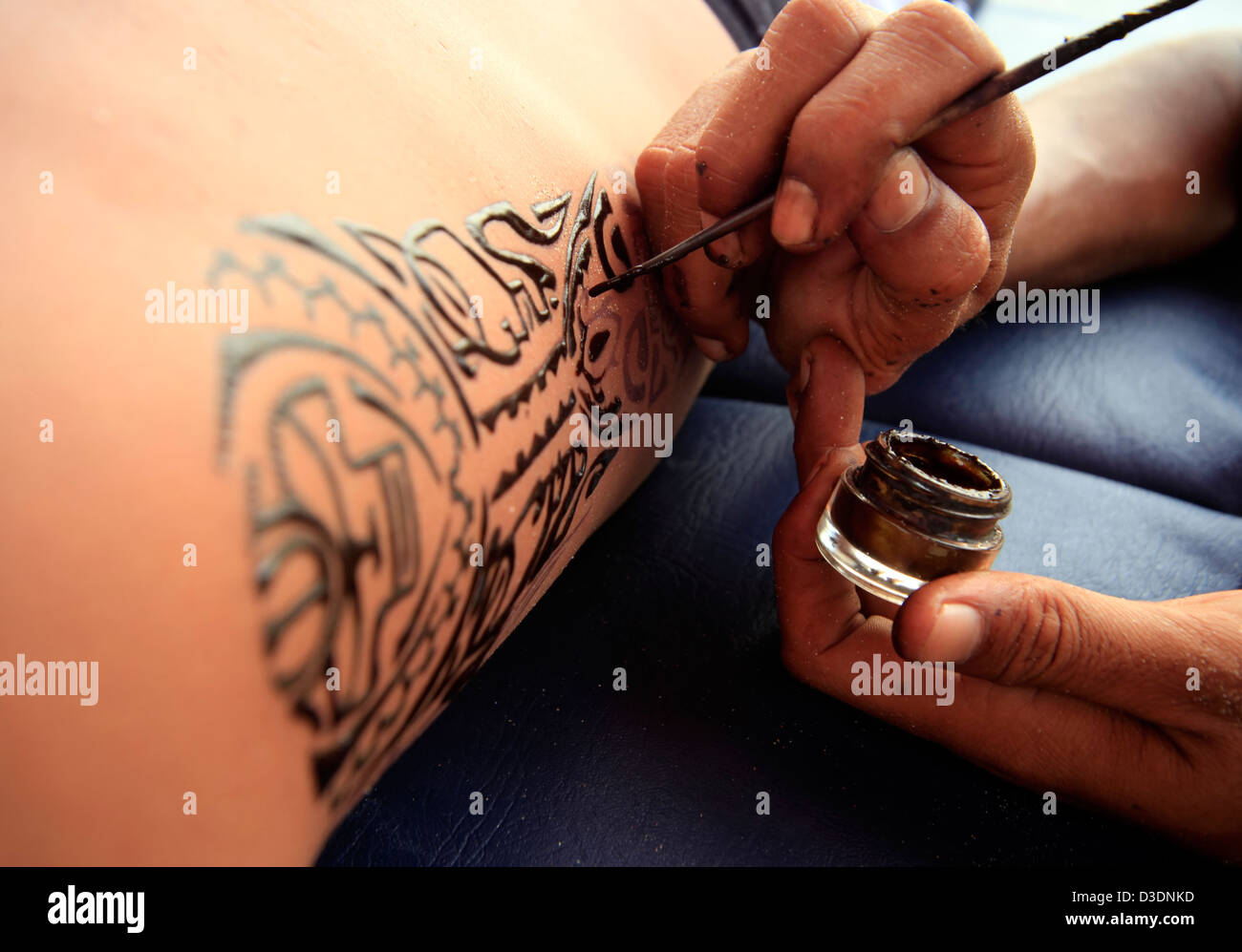 Künstler zeichnet ein Henna Tattoo auf einem männlichen Körper. Stockfoto