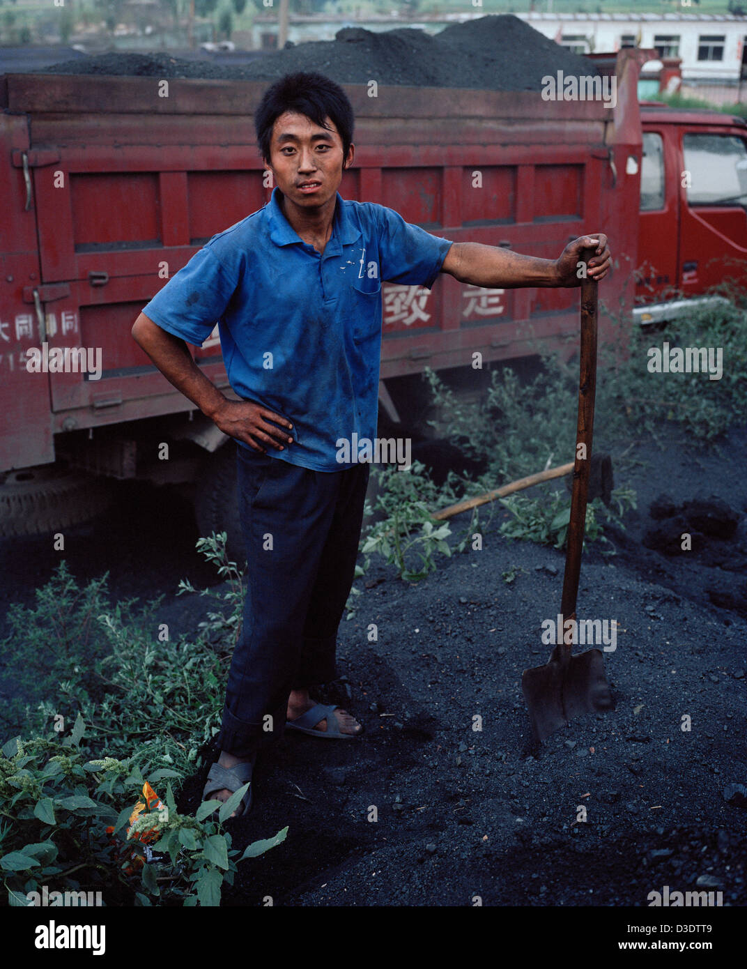 DATONG, Provinz SHANXI, CHINA - AUGUST 2007: 15 Jahre alter Junge Schaufeln Kohle Staub auf einen LKW mit zwei anderen Jugendlichen. Stockfoto