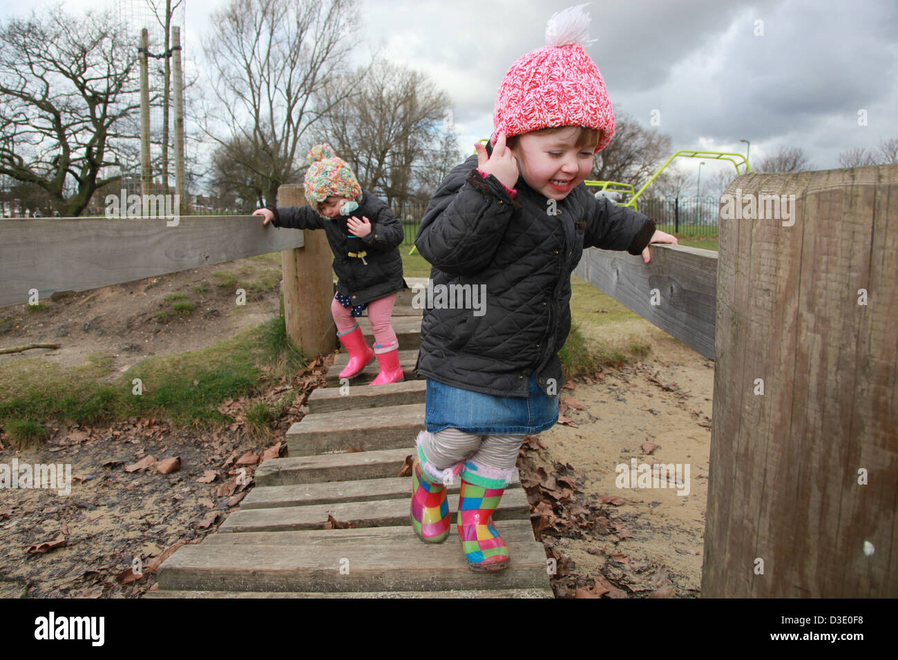 Kleinkind Zwillingsmädchen spielen im Park im Winter, UK Stockfoto