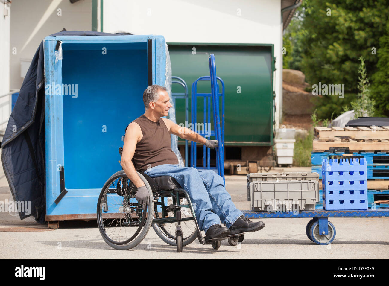 Laden Hafenarbeiter mit Querschnittslähmung im Rollstuhl bewegen einen Hand-LKW Stockfoto