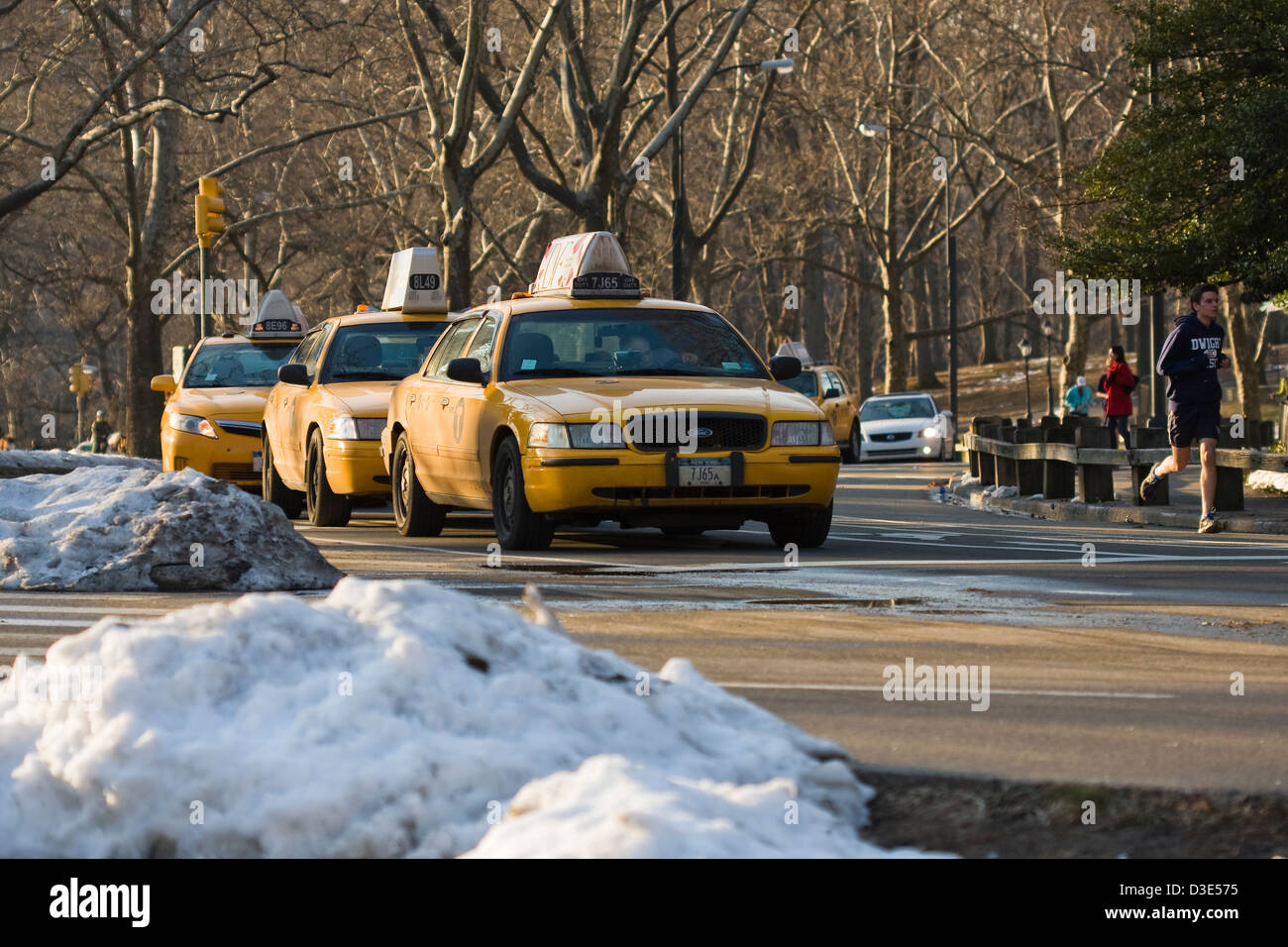 Gelben New Yorker Taxis aufgereiht und die Straße mit Jogger auf dem East Drive im New Yorker Central Park zu teilen Stockfoto