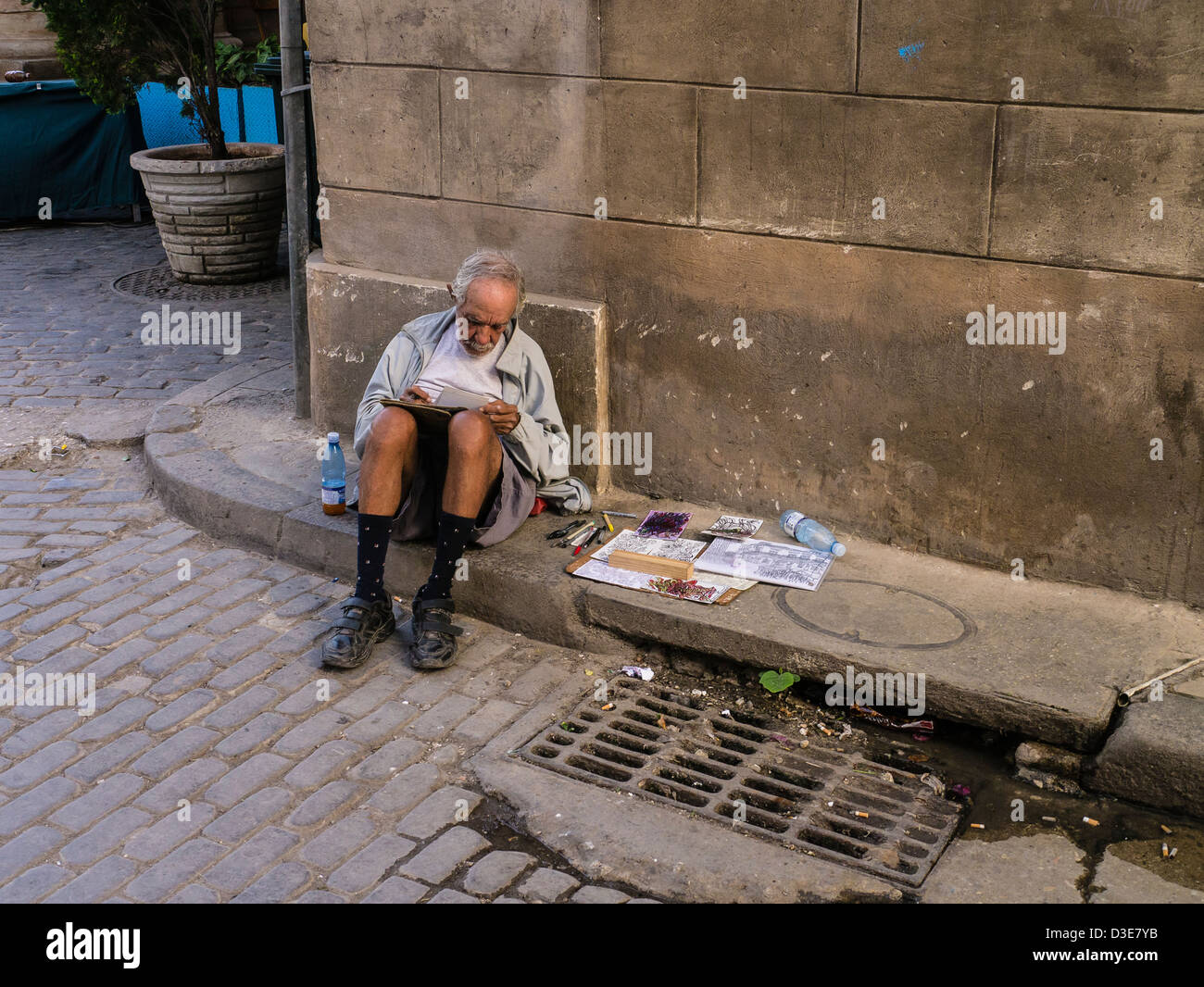 Ein Senioren-Künstler skizziert, wie er auf dem Bordstein ein Bürgersteig in Havanna, Kuba sitzt Stockfoto