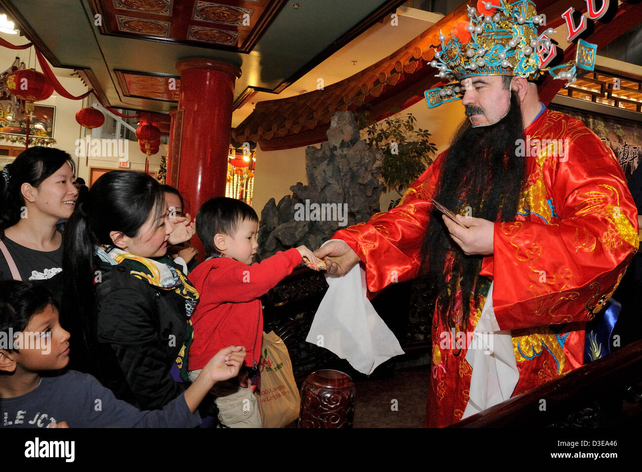 16. Februar 2013. Toronto, Kanada. Personal im Pacific Mall als chinesischen Gott des Reichtums - Tsai Shen Yeh, Geld Gott, austeilen rot gekleidet umhüllt, Kinder und Shopper als Glück und Wohlstand, das chinesische Neujahr zu feiern. Im Bild streckt 3 Jahre alten Brendan Chan für den roten Umschlag.  (DCP/N8N) Stockfoto