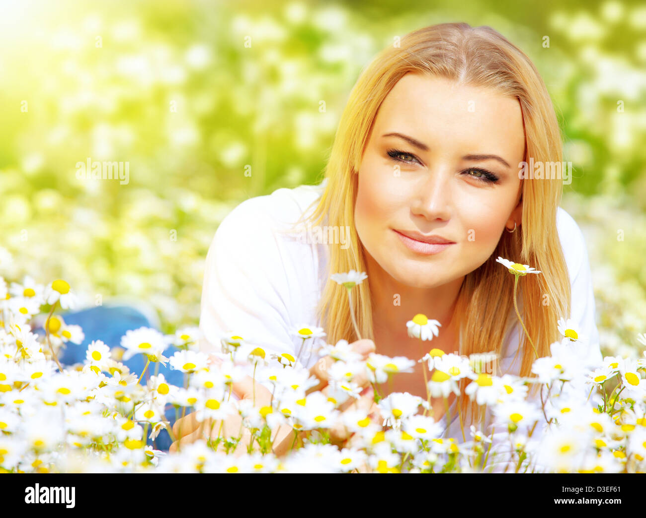 Bild von schönen weiblichen liegend auf Kamille Wiese in sonniger Tag, attraktive junge Dame ruht auf weißen Blüten Feld Stockfoto