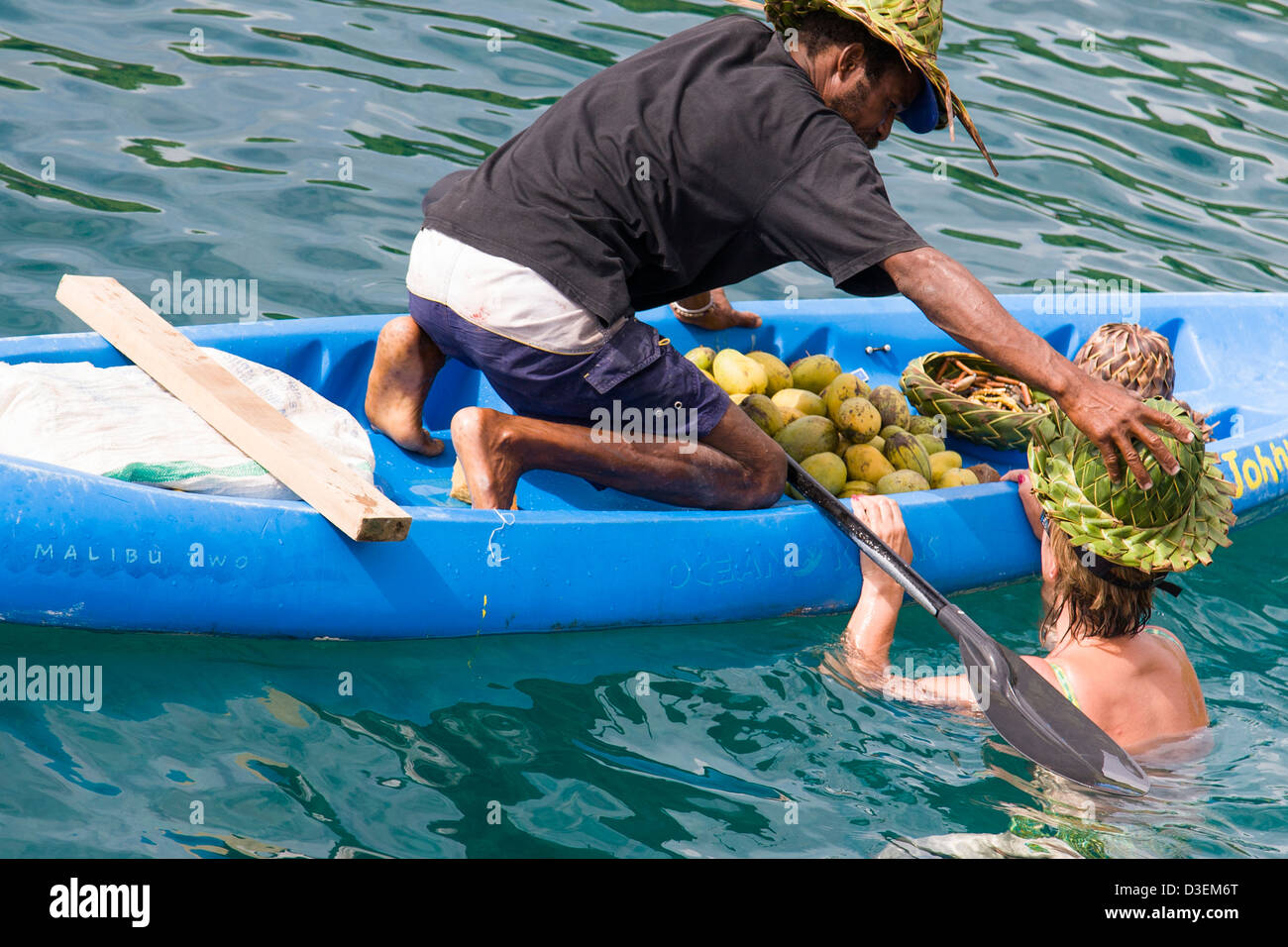 Frau Tourist schwimmt, eines Verkäufers Kanu einen Hut aus Bananenblättern Palm, St Lucia anprobieren. Stockfoto