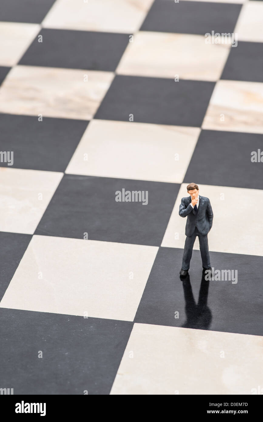 Kleine Figur des Geschäftsmannes auf Schachbrett stehen und denken, strategische Planung Stockfoto