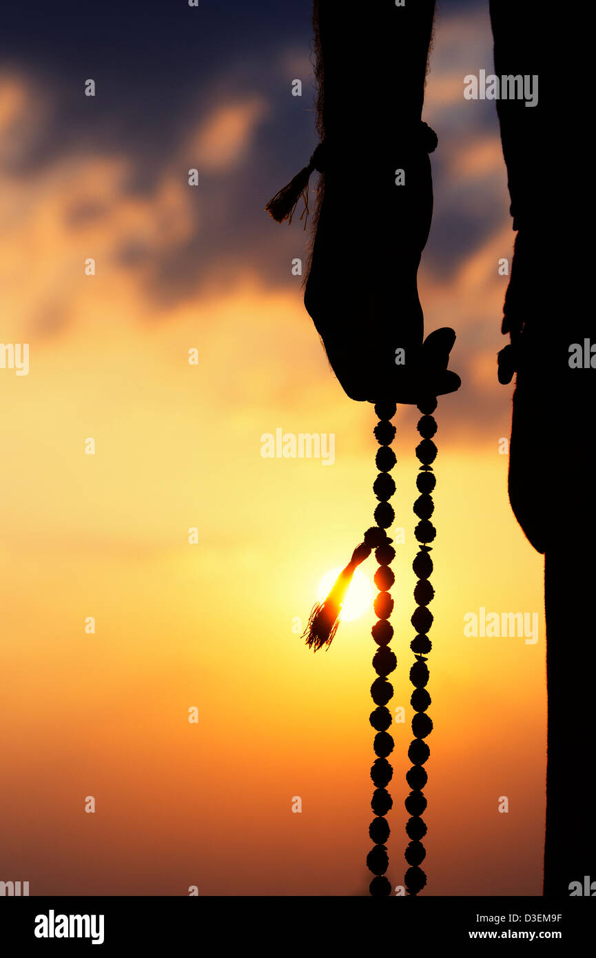 Mans Hand mit indischen Rudraksha / Japa Mala Gebetskette. Silhouette Stockfoto
