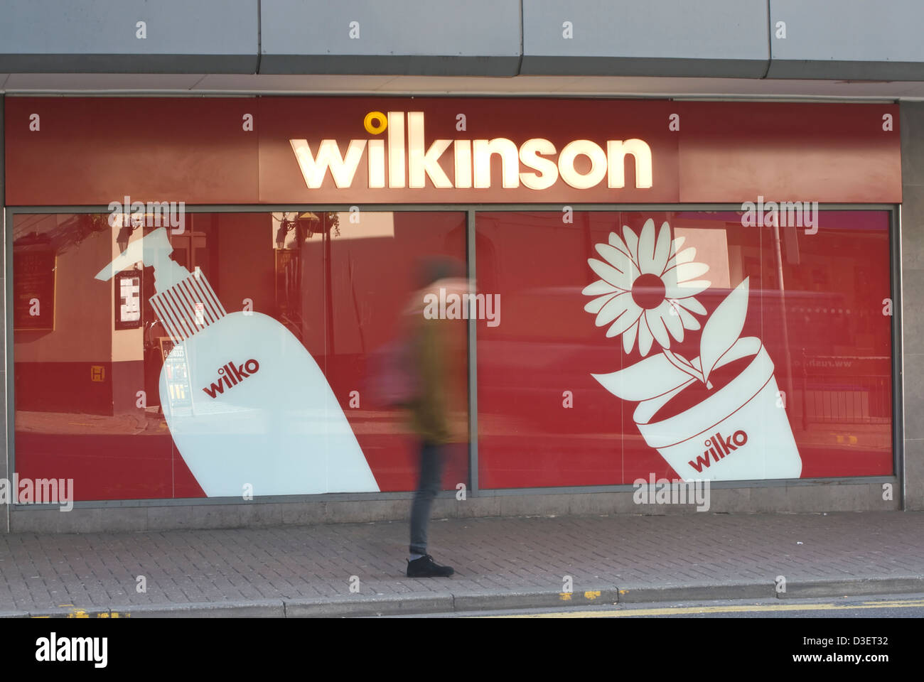 Frau gesehen in Bewegungsunschärfe zu Fuß draußen einen Banch von der High Street Einzelhändler, wilkinson Stockfoto