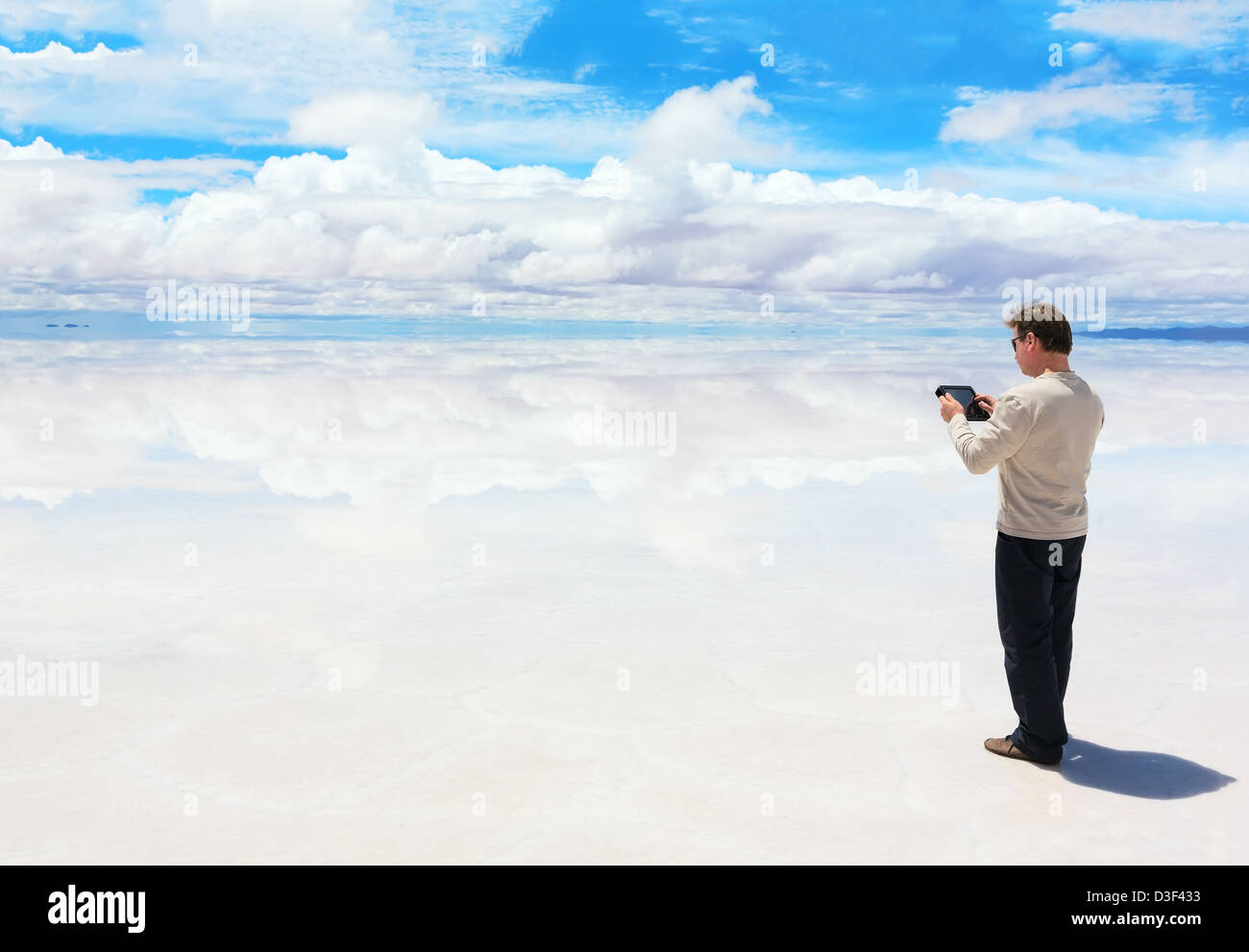 Mann, arbeitet auf einem digitalen Tablet in der Mitte des Sees Salar de Uyuni Stockfoto