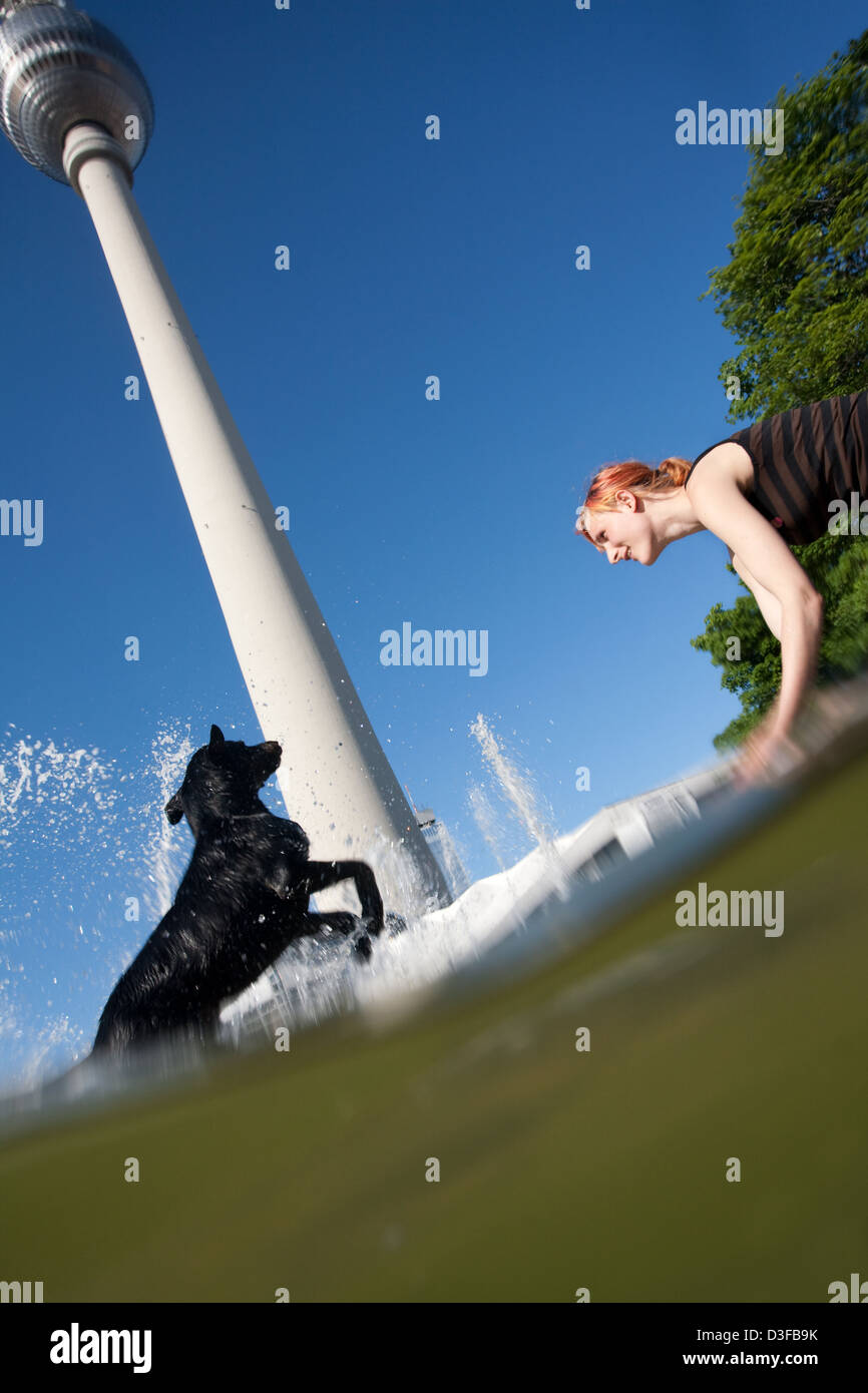 Berlin, Deutschland, Hund und Herrin bei den Kaskadenbrunnen mit dem Fernsehturm Stockfoto