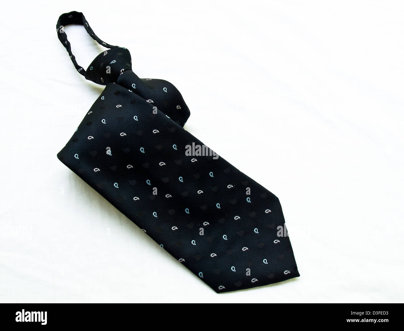 Eine gepunktete schwarze Krawatte isoliert auf weißem Hintergrund aufgerollt. Stockfoto
