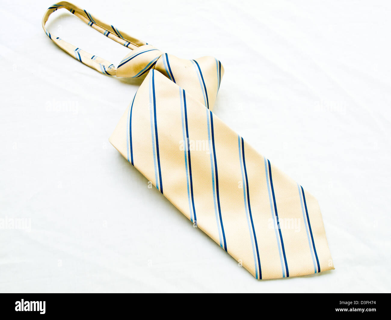 A aufgerollt gestreifte gelbe und blaue Krawatte isoliert auf weißem Hintergrund. Stockfoto