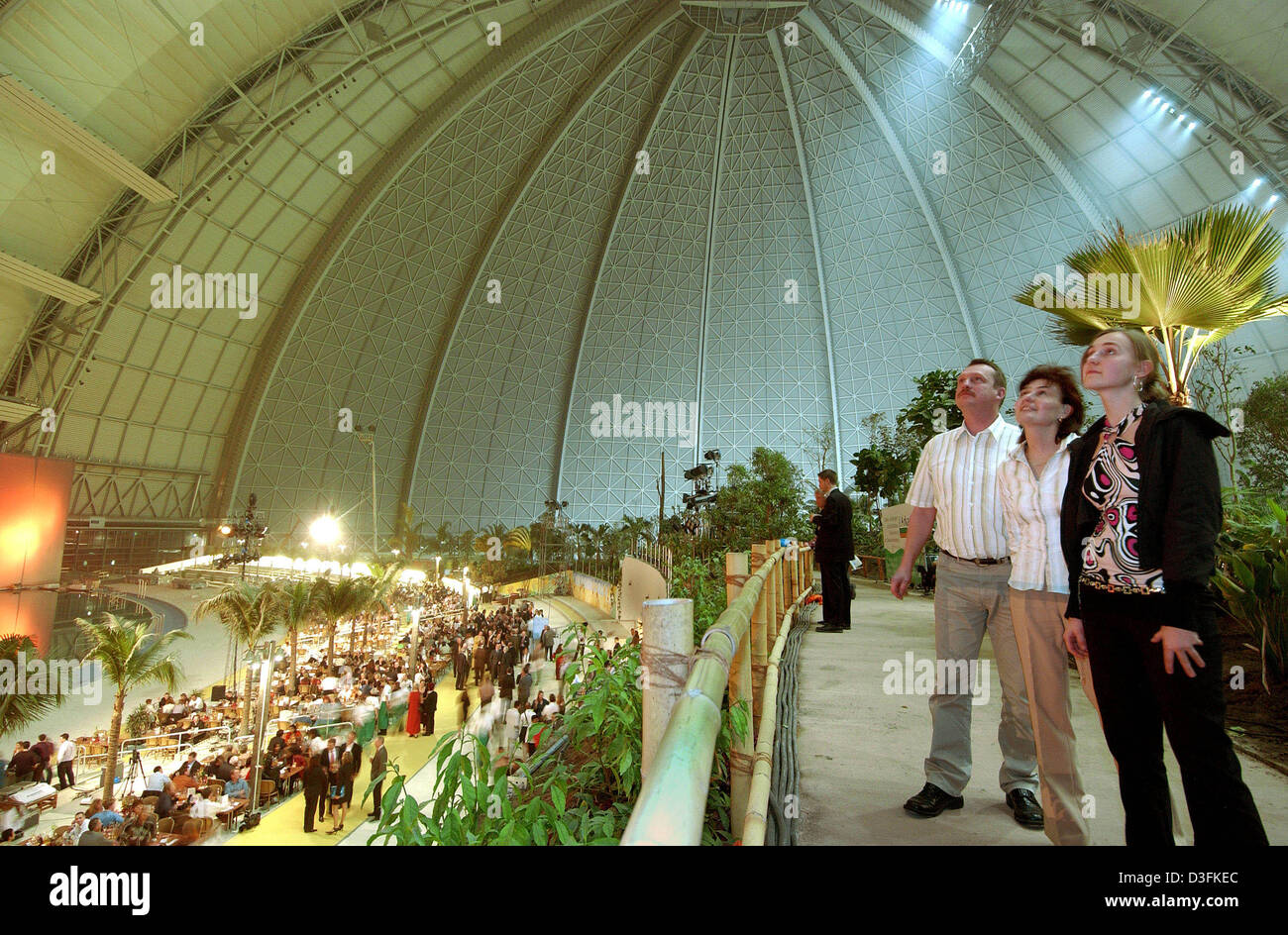 (Dpa) - Besucher stehen neben Palmen an das Tropical Islands Resort in Briesen-Brand, Deutschland, spät 16. Dezember 2004. Die tropische Landschaft öffnet am 19. Dezember 2004. Tropical Islands, eine 6,6 ha große Resort mit der größten freitragenden Halle der Welt, hat ein tropisches Klima das ganze Jahr. Es besteht aus einem tropischen Meer, Strand, Lagunen und ein Regenwald mit einem tro Stockfoto