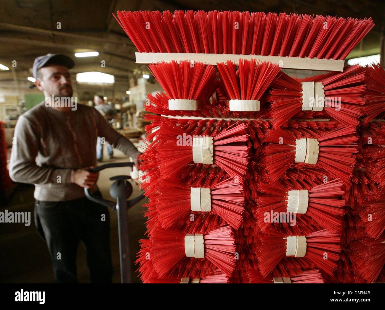 (Dpa) - ein Mitarbeiter A & A Brueck Brushmaker Unternehmens bewegt sich eine Palette von handgefertigten roten Besen in Ramberg, Deutschland, 13. September 2004. Die Stadt Ramberg hat eine lange Tradition in Brushmaking seit dem Ende des 18. Jahrhunderts. Stockfoto