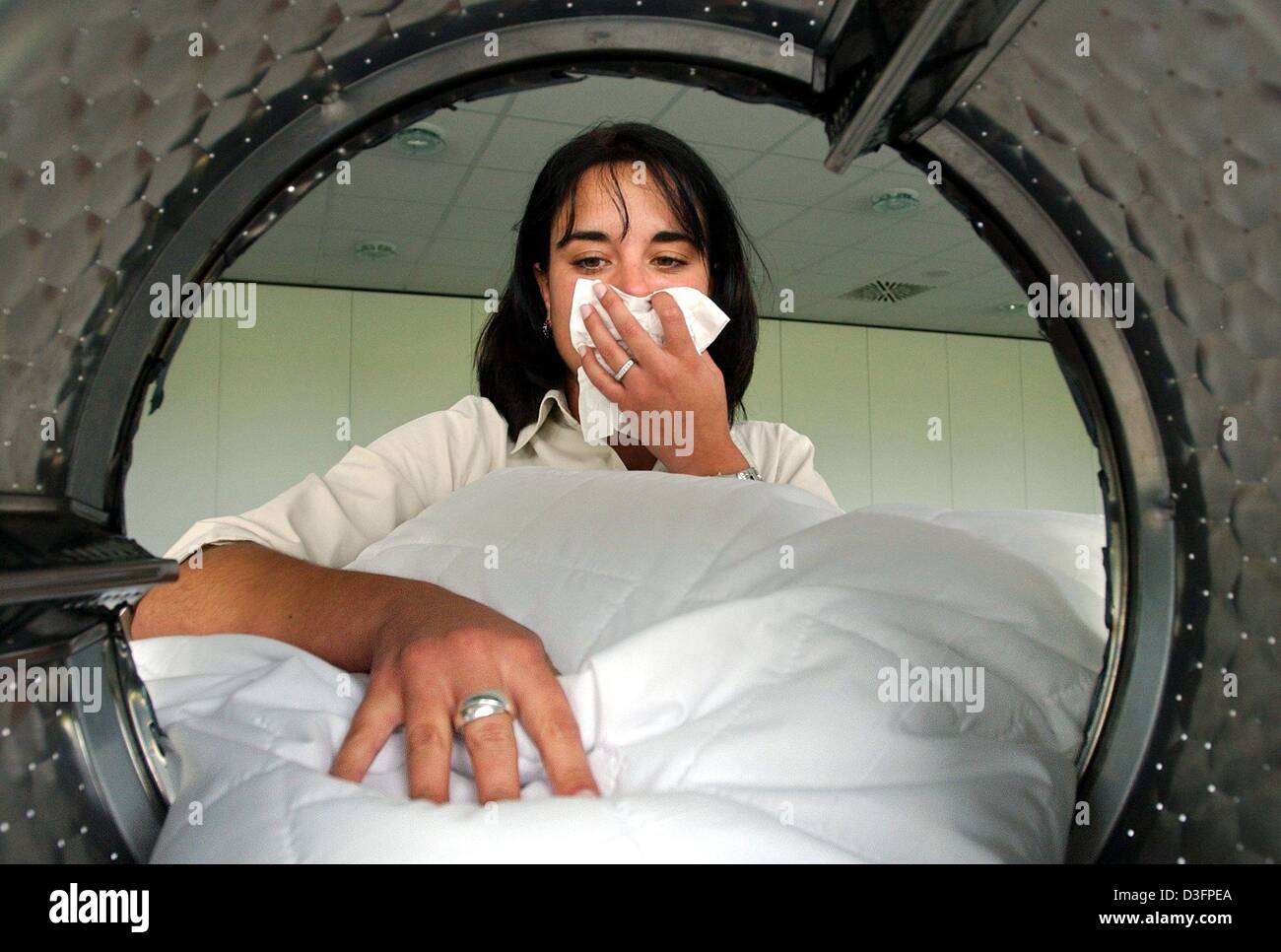 Dpa) - eine junge Frau bedeckt ihr Gesicht mit einem Taschentuch beim Laden  ihre neue Waschmaschine, die speziell für Allergiker in München, 9. Mai  2003 entworfen wurde. Waschmaschinenhersteller Miele präsentiert die  Weltneuheit,