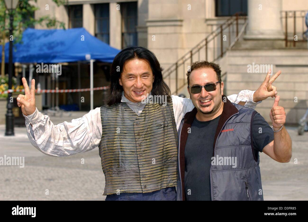 (Dpa) - Movie Regisseur Frank Coraci ("The Wedding Singer", "The Waterboy") und Actionstar Jackie Chan (L) sind posiert und Sieg und Daumen-hoch-Zeichen vor einer Pressekonferenz auf dem Schießen von "Around the World in 80 Days" in Berlin, 6. Mai 2003. Chan spielen Passepartout und britischer Komiker Steve Coogan spielt Phileas Fogg in dem 100 Millionen-Dollar-Fantasy Abenteuer-Remake des Stockfoto