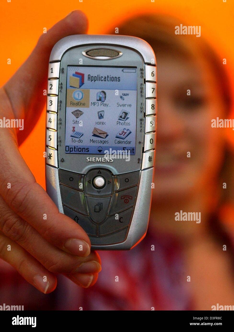 (Dpa) - Sabine zeigt das neue SX1 Handy auf dem Messegelände in Hannover, Deutschland, 11. März 2003. Das Telefon verfügt über eine integrierte Kamera, Farbdisplay, MP3-Player, Radio und Bluetooth-Technologie. Die CeBIT, der weltweit größten Computermesse, wird voraussichtlich vom 12. bis 19. März 2003 stattfinden. Mehr als 6.500 Unternehmen aus der ganzen Welt sollen prese Stockfoto