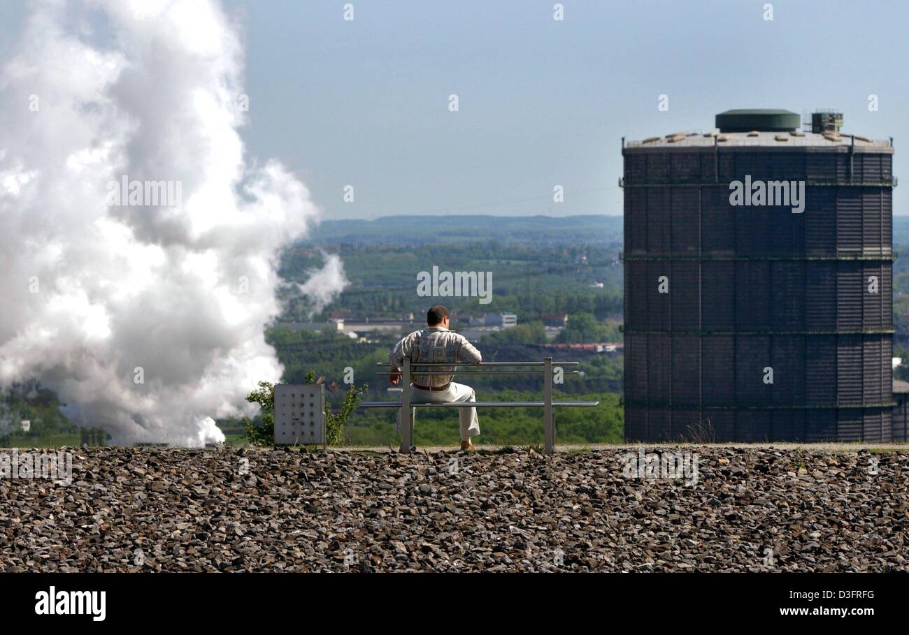 (Dpa) - ein Mann sitzt auf einer Bank auf einem ehemaligen Haufen und schaut auf die Landschaft und die Kokerei Prosper in Bottrop, Deutschland, vor ihm 3. Mai 2003. Die lokale Community Association Kommunalverband Ruhrgebiet (KVR) bietet der Entdeckerpass 2003 (Discovery pass 2003) die Besucher auf einem Rundgang durch die industrielle Kultur und Geschichte der das Ruhrgebiet führt. Besucher-c Stockfoto