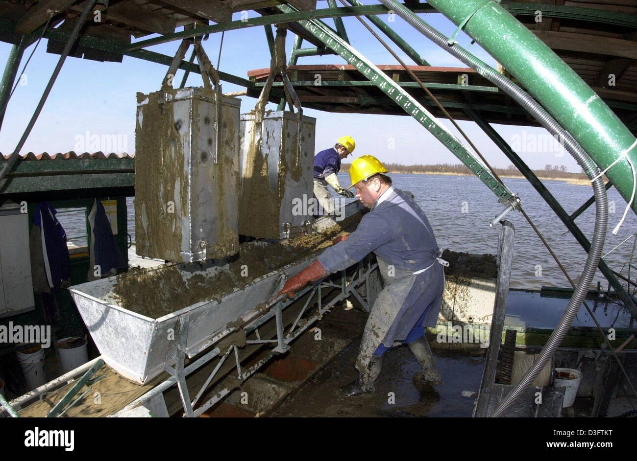 (Dpa) - Mitarbeiter der "Pelose-Heilschlamm GmbH Schollene" Heilschlamm aus dem See 'Schollener See', Deutschland, 15. April 2003 bekommen. Metall-Boxen werden verwendet, um jedes Jahr ca. 1.500 Tonnen von Schlamm aus dem Gelände des Sees zu gewinnen. Über einen Zeitraum von 10.000 Jahren haben abgestorbene Algen eine Schicht von 16 Kubikmeter Schlamm am Boden des Sees gebildet. In der Physiotherapie, Dermatologie und Balneologie Stockfoto