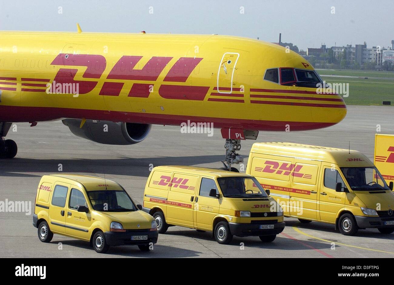 (Dpa) - eine Boeing und Fahrzeuge, die mit dem Logo von DHL stehen am Flughafen Tempelhof in Berlin, 30. April 2003. Ab dem 1. Mai wird der Deutschen Post eine weltweite Werbekampagne für DHL, die neue Parzelle Express und Logistik-Dienstleistungen weltweit operierenden starten. Stockfoto