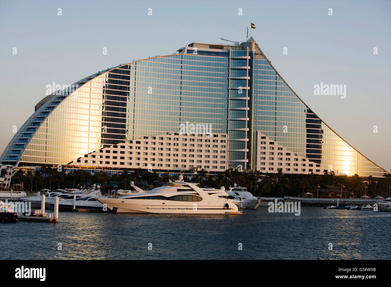 Jumeirah Beach Hotel Dubai mit einer Luxusyacht im Vordergrund bei Sonnenuntergang Stockfoto