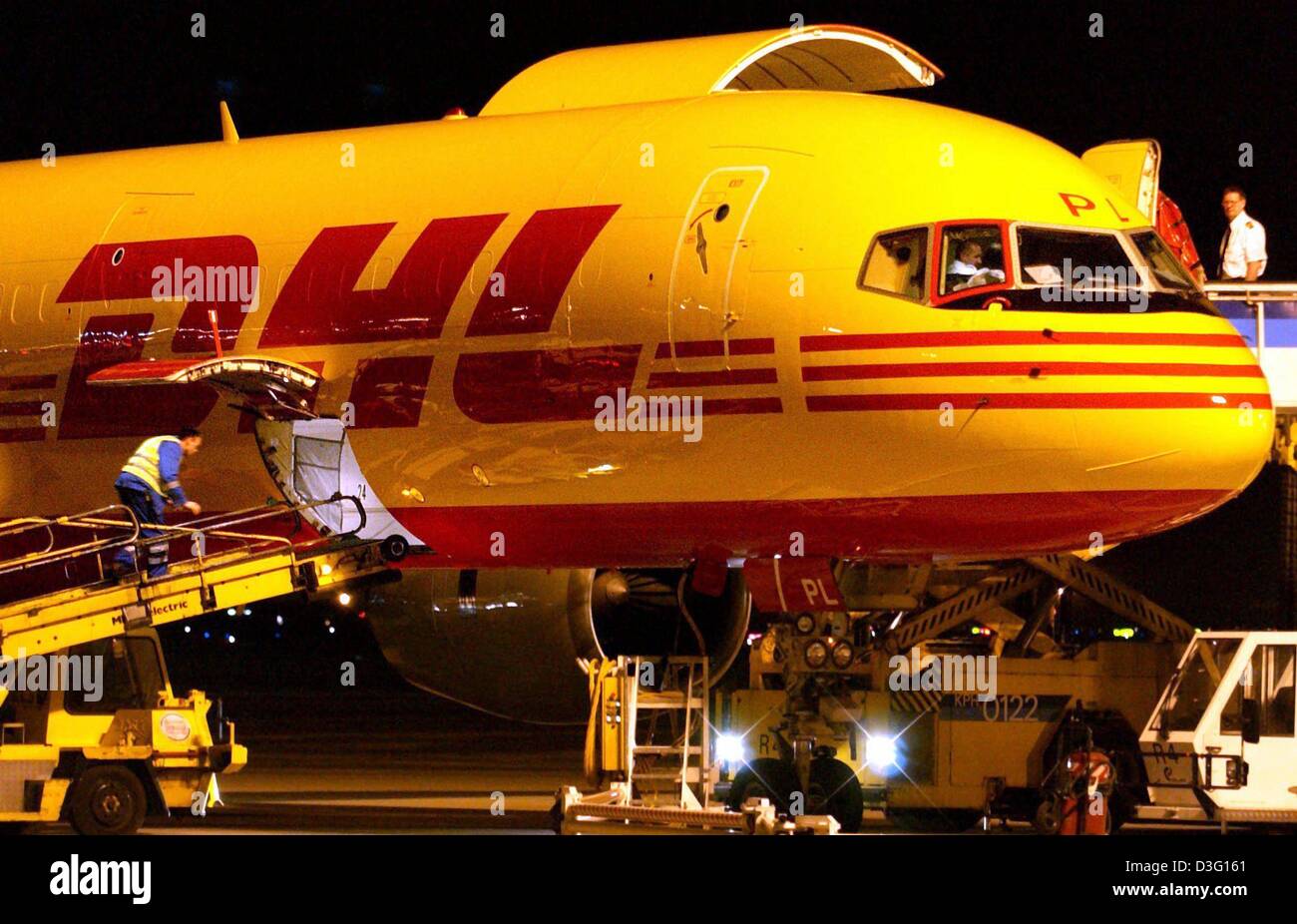 (Dpa) - ein Frachtflugzeug ist entladen wird in der Nacht auf dem Flughafen in Frankfurt am Main, 28. März 2003. Im Zuge der laufenden rebranding der Fracht-Unternehmen DHL wird die Flotte von Flugzeugen gelb lackiert. DHL Logistik-Partner, die Deutsch Post (Deutsche Post), gelten auch diese Farbgebung für ihre Flotte von Autos und Fahrzeuge transportieren. Bisher Flugzeuge und Kooperationsfähigkeit Stockfoto