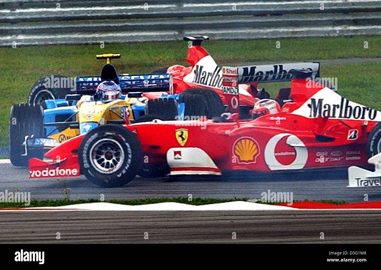 (Dpa) - deutscher Formel-1-Weltmeister Michael Schumacher (Ferrari) fährt gegen italienische Fahrer Jarno Trulli (Renault) (L) in der dritten Kurve nach dem Start auf dem Formel 1 Rennen zu verfolgen, während der Formel 1-grand-Prix-Rennen in Sepang in der Nähe von Kuala Lumpur, Malaysia, 23. März 2003. Italienischer Formel-1-Fahrer Rubens Barrichello (Ferrari) (R) überholt beide Fahrer auf der Rennstrecke. Schu Stockfoto