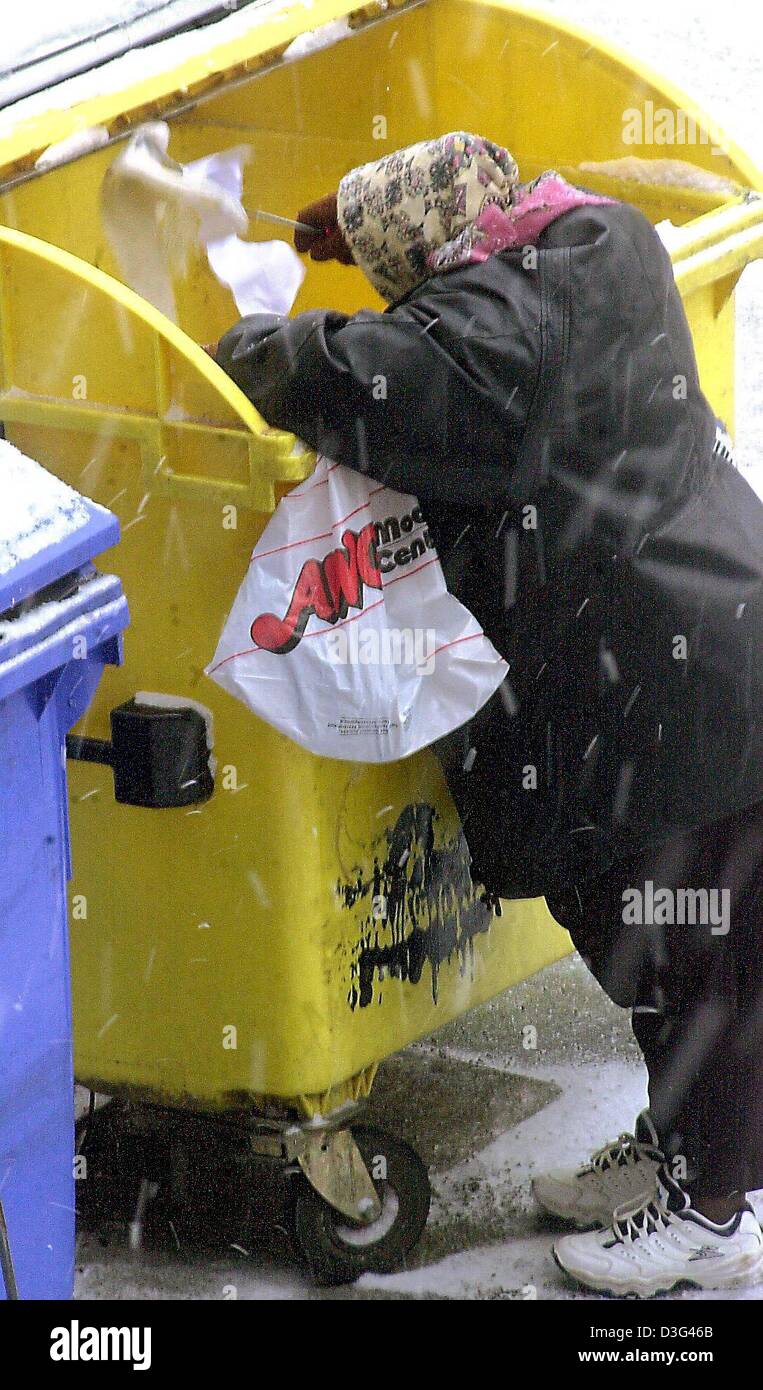 (Dpa) - kramt eine Frau durch den Inhalt eines großen gelb-farbigen recycling Containers während eines Schneesturms in Berlin, Deutschland, 31. Januar 2003. Stockfoto