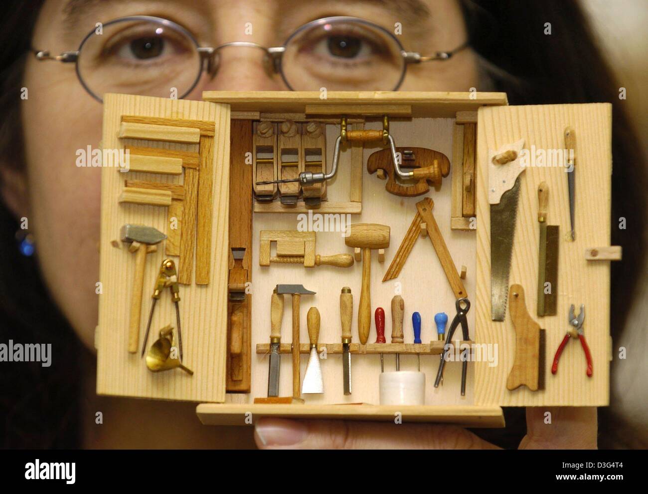 (Dpa) - Ulrike Schwarz präsentiert eine Schachtel mit Miniatur-Werkzeuge im Handwerk Museum in Deggendorf, Deutschland, 12. Dezember 2003. Die kleinen Kunstwerke im Maßstab 1:9 sind voll funktionsfähig und wurden vom Künstler Franz Zanella geschaffen. Stockfoto