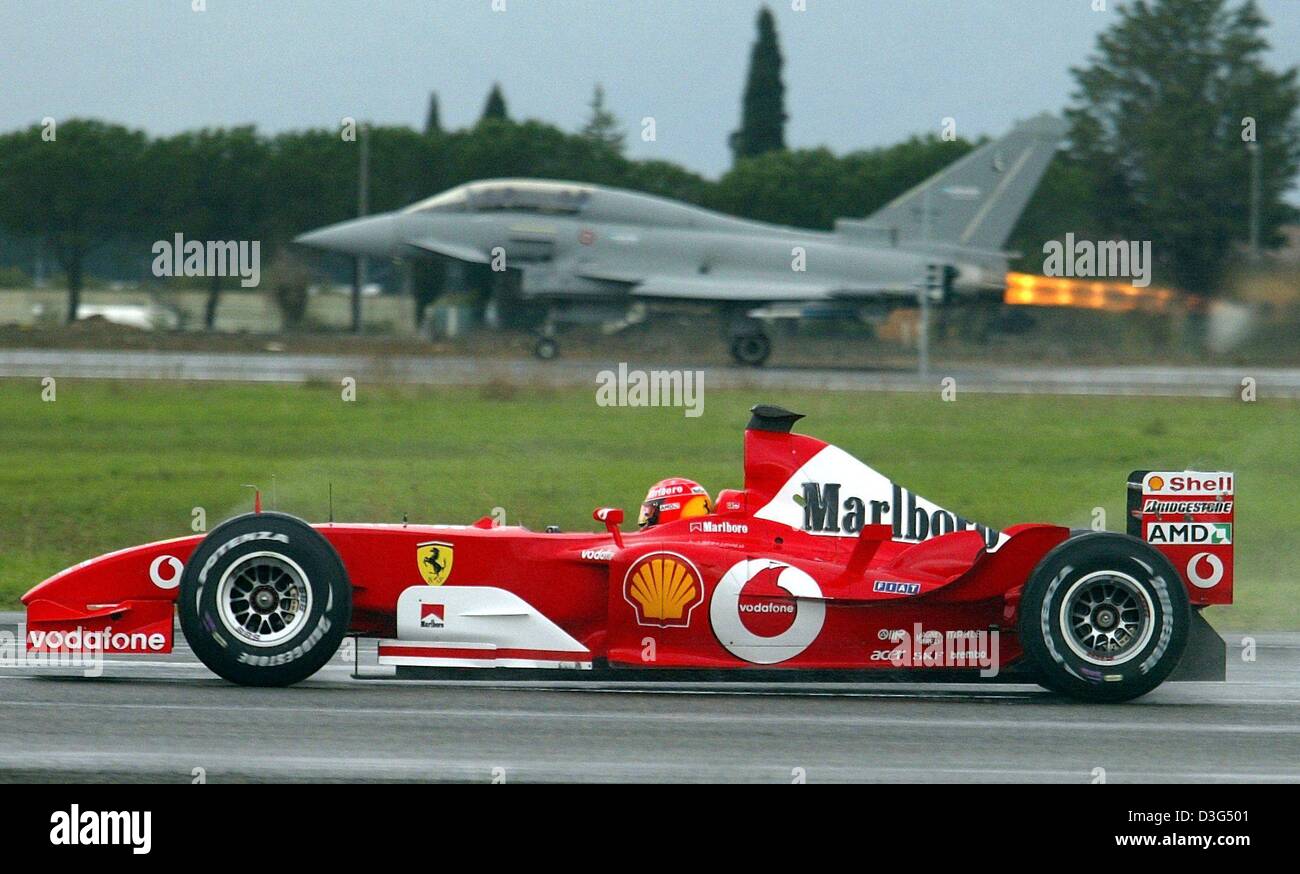 (Dpa) - deutsche Formel 1 pilot und Weltmeister Michael Schumacher (vorne) in seinem Ferrari F2003-GA gegen den Eurofighter auf einem Militärflugplatz in Grosseto, Italien, 11. Dezember 2003 Rennen. Schumacher gewann sogar das Rennen, das eine Strecke von 500 Metern zurückgelegt. Jedoch konnte Düsenjäger Maurizi Cheli weitere Rennen, zu entscheiden, welche Entfernungen von 1.000 bis 1.500 Meter bedeckt Stockfoto