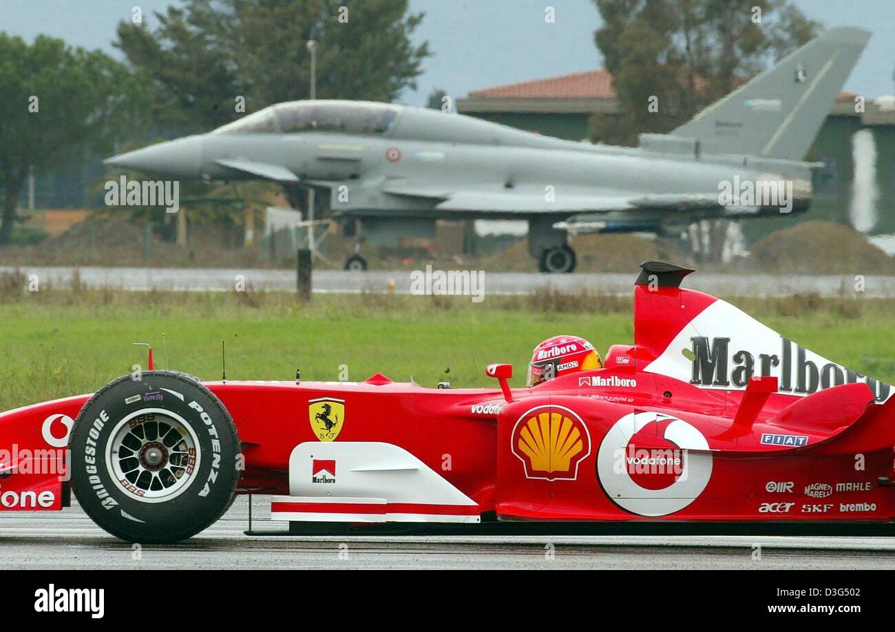 (Dpa) - deutsche Formel 1 pilot und Weltmeister Michael Schumacher (vorne) in seinem Ferrari F2003-GA gegen den Eurofighter auf einem Militärflugplatz in Grosseto, Italien, 11. Dezember 2003 Rennen. Schumacher gewann sogar das Rennen, das eine Strecke von 500 Metern zurückgelegt. Jedoch konnte Düsenjäger Maurizi Cheli weitere Rennen, zu entscheiden, welche Entfernungen von 1.000 bis 1.500 Meter bedeckt Stockfoto