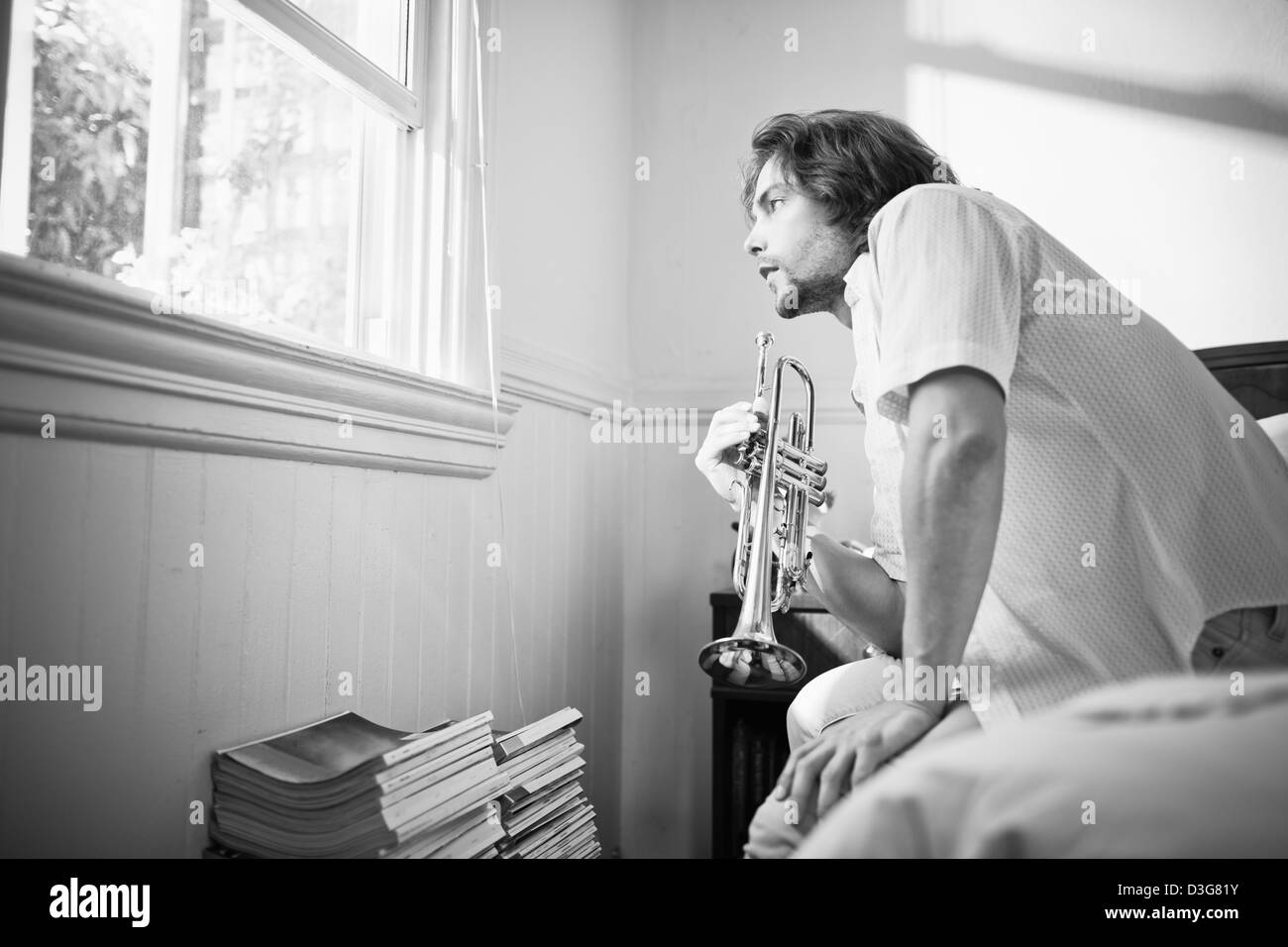 Junge männliche Trompeter üben zu Hause im Bett. Stockfoto