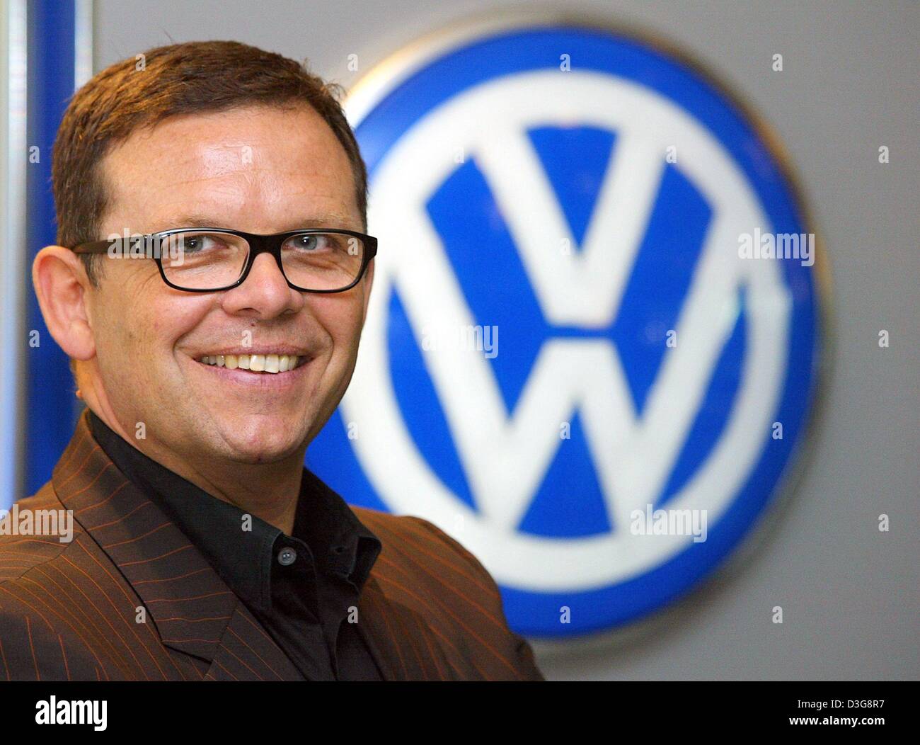 (Dpa) - Auto-Designer Peter Schreyer lächelt, während er vor dem VW-Logo auf dem Automobil Forum in Berlin, 15. Oktober 2003 steht.  Schreyer wurde der deutsche Designer Award ausgezeichnet. Er hatte Audi seit vielen Jahren tätig und heute leitet er die Design-Abteilung von VW in Wolfsburg, Deutschland. Schreyer war insbesondere zuständig für die Pkw-Modelle von Audi TT und Audi A6. Th Stockfoto