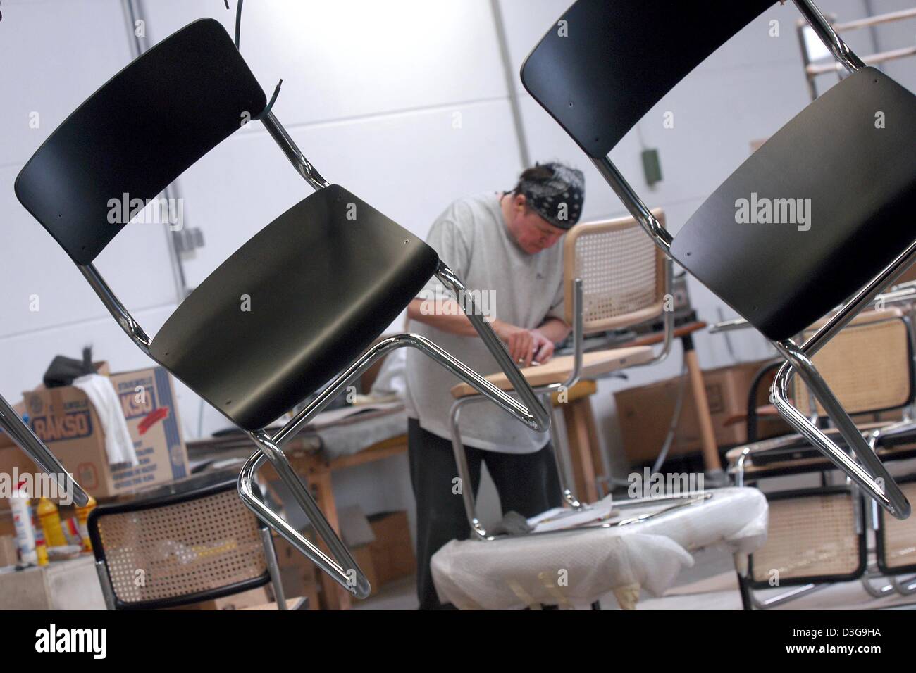(Dpa) - Platz für Stühle der S43 Modell hängen an Haken während ein Arbeitnehmers eine S32 überprüft in der Seatfactory Thonet in Frankenberg, Deutschland, 10. März 2004. Thonet entworfen, das meistverkaufte Sitz aller Zeiten, der Kaffeehausstuhl Nr. 14 (Coffeeshop Stuhl Nr. 14), von denen 50 Millionen Stück weltweit verkauft wurden. Die Firma entstand im Jahre 1819 von Michael Thonet eigene Desi produzieren Stockfoto