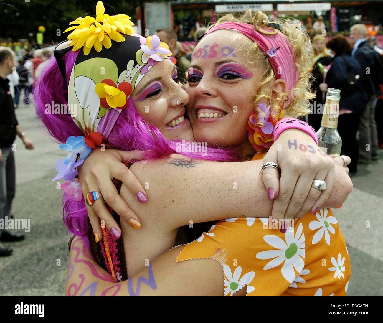 (Dpa) - zwei bunt gekleidete junge Frauen umarmen einander, wie sie durch die Straßen während der Schlagermove-Parade entlang der Hamburger Reeperbahn, Deutschland, 3. Juli 2004 tanzen. Die größten Schlager-Musik-Parade in Deutschland fand zum achten Mal mit einigen 300.000 Fans besucht. 36 Musik schwebt brachte die Flower-Power der 70er Jahre wieder auf den Straßen von Hamburg. Stockfoto