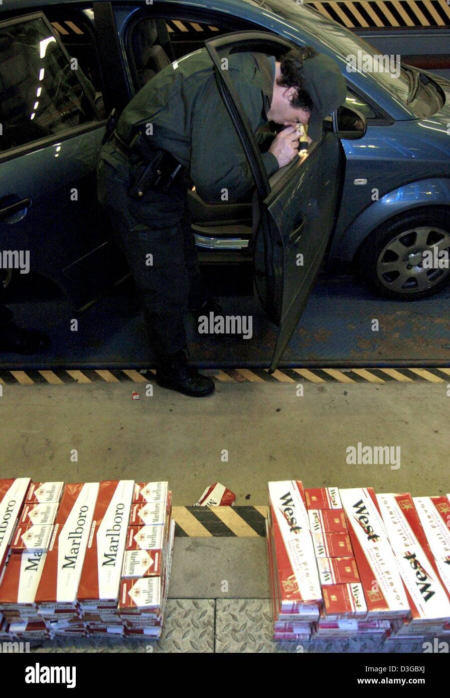 (Dpa) - ein Zollbeamter sucht eine polnische Auto für geschmuggelte Zigaretten in einem Zollhalle in Frankfurt/Oder, Deutschland, 20. Oktober 2004. Das Auto war vorher gestoppt und von einer mobilen Kontrollgruppe an der Autobahn in der Nähe von Frankfurt/Oder durchsucht. Nach einer kurzen Inspektion wurde ein Doppelboden mit ca. 100 Stangen Schmuggelzigaretten entdeckt. Obwohl keine Kostüme Offiziere stationiert sind Stockfoto