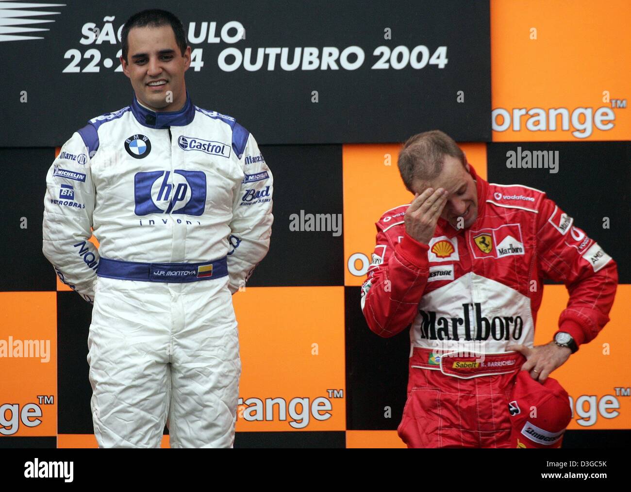 (Dpa) - steht kolumbianische Formel-1-Fahrer Juan Pablo Montoya (L) von BMW-Williams auf dem Podium mit Drittplatzierte brasilianischen Rubens Barrichello (Ferrari) nach dem Gewinn der brasilianischen Formel Eins Grand Prix auf der Rennstrecke Interlagos in Sao Paulo, Brasilien, 24. Oktober 2004. Stockfoto