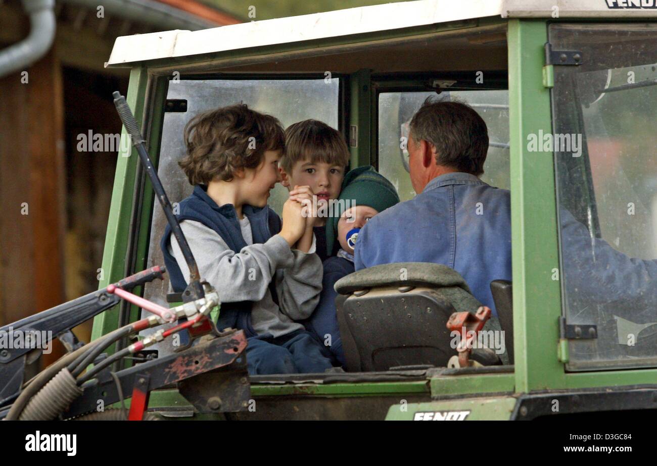 (Dpa) - drei Kinder begleiten der Bauer auf seinem Traktor auf einem Bauernhof in Hirschzell, Süddeutschland, 2. Oktober 2004. Vor allem Familien mit kleinen Kindern genießen ihren Urlaub auf einem Bauernhof, wo die Kinder im täglichen Routinen teilnehmen können. Stockfoto