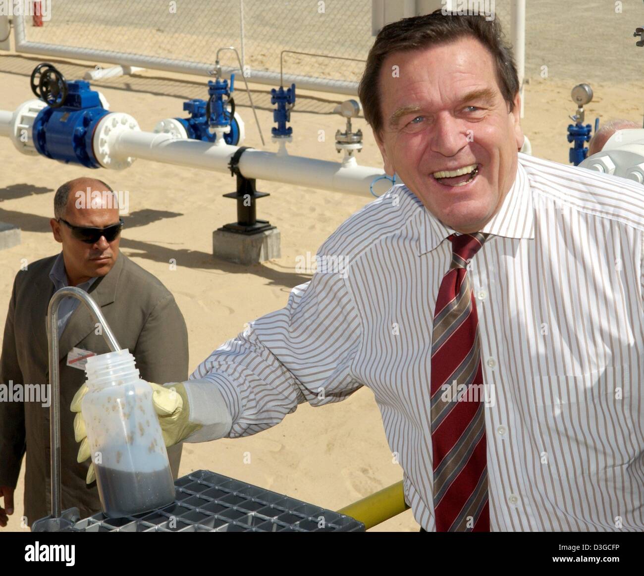 (Dpa) - Bundeskanzler Gerhard Schroeder hält eine Ölprobe in seinen Händen, in der Wüste Libyens auf Freitag, 15. Oktober 2004. Schröder eröffnet vor das neue Öl Rig A11 der deutschen Unternehmen Wintershall AG, eine Tochtergesellschaft der BASF. Schroeder ist bei einem zweitägigen Jungfernfahrt Besuch in Libyen, die erste jemals von einem deutschen Führer in 25 Jahren. Stockfoto