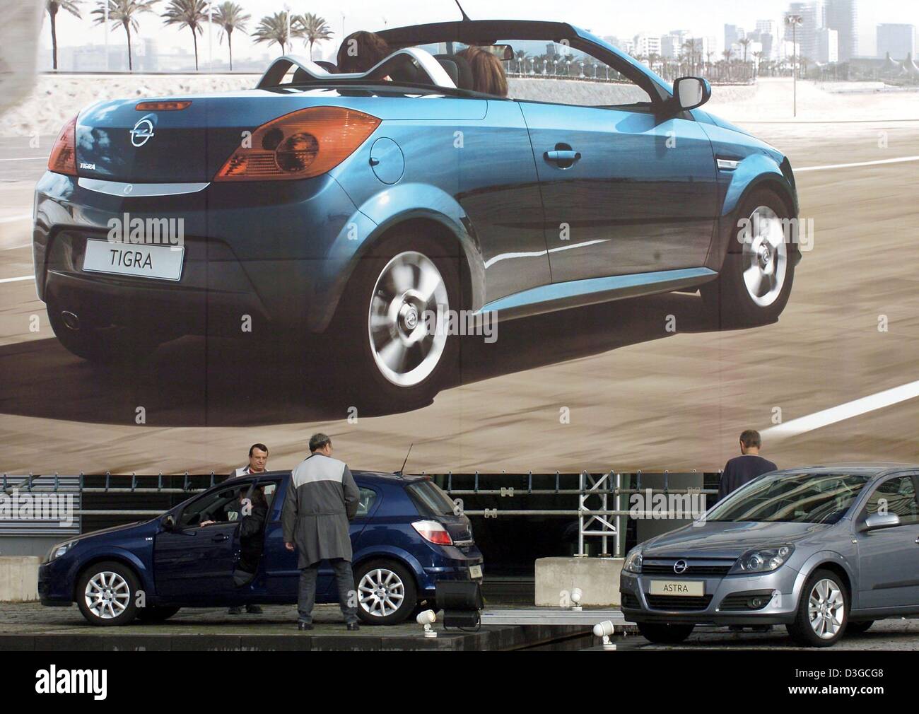 (Dpa) - Opel-Mitarbeiter parken zwei Opel Astras vor einem riesigen Plakat Werbung der Opel Tigra Twin Top auf dem Gelände der Autobauer Opel in Rüsselsheim, Deutschland, 15. Oktober 2004. Die Pflanze Arbeiterrat die schlimmsten Befürchtungen wahr am Donnerstag 14. Oktober als US-Autohersteller General Motors (GM) präsentiert die Kostenersparnis Plan für seine europäischen Sudsidiaries Opel, Saab und Vauxhall Stockfoto