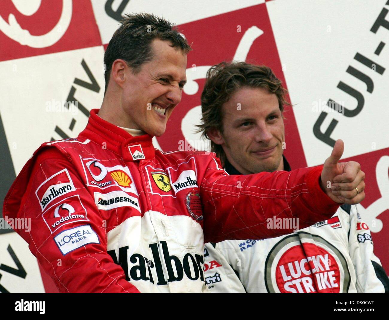 (Dpa) - Michael Schumacher (L, Ferrari), deutsche Formel 1 Weltmeister, wirft seinen Daumen neben britischen Formel-1-Fahrer Jenson Button (BAR-Honda) bei der Siegerehrung nach dem Gewinn des Grand Prix auf der Rennstrecke in Suzuka, Japan, 10. Oktober 2004. Michael Schumacher gewann das Rennen, gefolgt von seinem Bruder Ralf Schumacher (BMW-Williams), die im zweiten und Taste w kamen Stockfoto