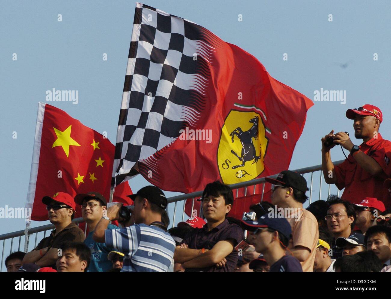 (Dpa) - Chinesisch fans mit einem Ferrari und einem chinesischen Nationalflagge sehen den chinesischen Grand Prix auf dem neuen Shanghai International Circuit in Shanghai, China, 26. September 2004. Stockfoto