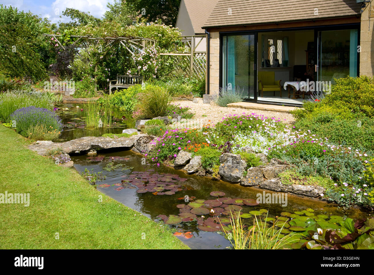 Britische Gärten. Ein reifen Garten Teich, der von einem Innenhof und Garten Zimmer. Stockfoto