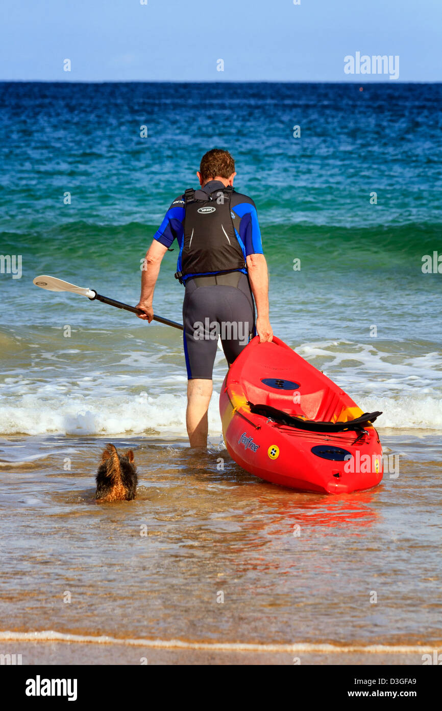 Reifer Mann mit einem Kanu und Hund, Harlyn Bay, Cornwall, England Stockfoto